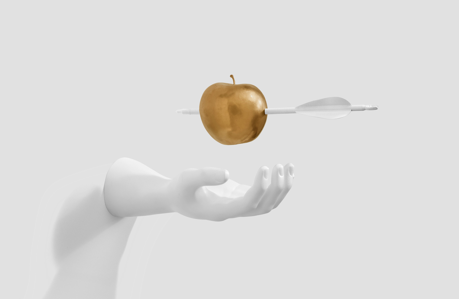 Mano a punto de sostener una manzana dorada atravesada por una flecha