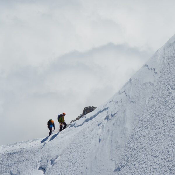 Pareja de escaladores subiendo por una colina helada
